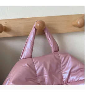 Detail of soft quilted handles on a pale pink padded backpack with metallic finish
