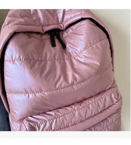 Detailed view of pink quilted puffer backpack fabric with soft texture and black zipper