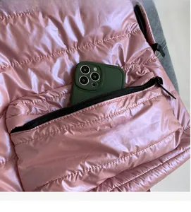 Detailed close-up of the front zipper pocket on this pink quilted puffer backpack