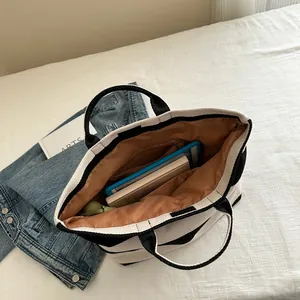 Large striped canvas tote bag with black stripes showing spacious interior and laptop