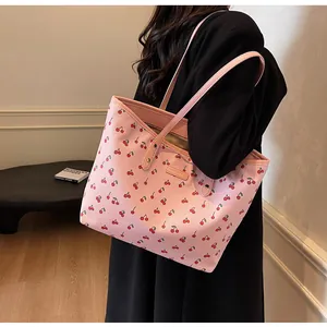 Dettaglio borsa shopper rosa con stampa ciliegie indossata da modella in interno