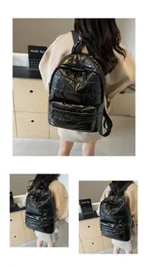 Detail of black quilted puffer backpack showing zipper pocket and glossy nylon texture