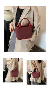 Detail der burgunderroten Bucket Bag aus mattem Leder mit geknotetem Griff und Logoplatte