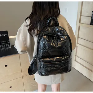 Rear view of a model wearing a glossy black quilted backpack made of padded nylon fabric