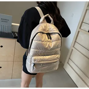 Detail of metallic quilted backpack featuring shiny silver fabric and puffer texture
