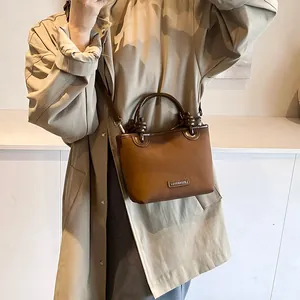 Braune Vintage-Eimertasche aus mattem Leder mit Griff und Schultergurt an einem Model
