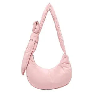 Pink quilted half-moon shoulder bag with oversized bow detail and adjustable strap