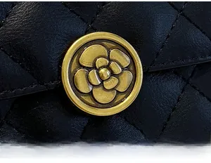 Détail macro du portefeuille en cuir noir matelassé avec boucle en métal fleur de camélia
