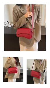 Detail view of red lychee grain leather crossbody bag with wave flap and gold hardware