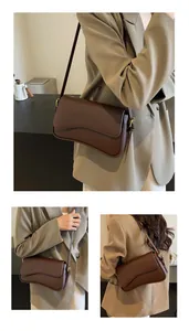 Detailed view of dark brown pebbled leather shoulder bag with wavy flap design and gold buckle