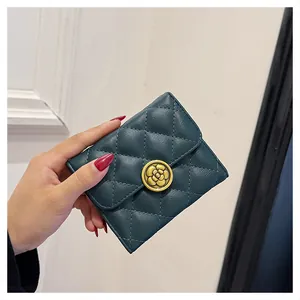 Gros plan d'un portefeuille vert en cuir matelassé avec boucle en métal camélia dorée