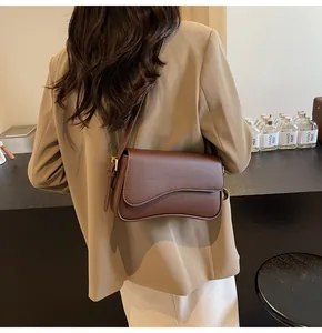 Detailed back view of a dark brown litchi pattern leather crossbody bag on a model