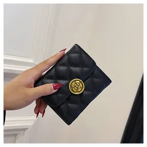 Gros plan d'un petit portefeuille matelassé noir avec fermoir fleur de camélia doré
