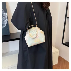 Detalle de bolso vintage con cierre de clic, bordado floral y asa de perlas