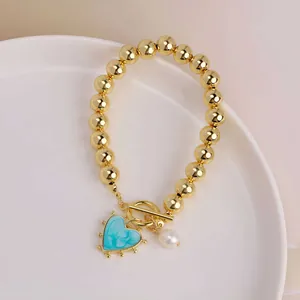 Detail of 18K gold beaded bracelet with blue heart pendant and freshwater pearl with OT clasp