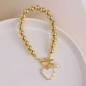 Detail of 18K gold OT buckle bracelet with heart pendant and water drop pearl