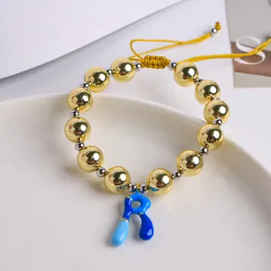 Detalle macro de cuentas de oro 18K y dije de letra R esmaltada en pulsera tejida