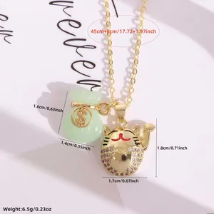 Detail van 18K vergulde ketting met jade geldzakje en gelukskat hangers op een witte schaal