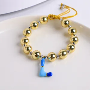 Detalle de pulsera de cuentas de oro 18K con colgante letra L en esmalte azul y cordón