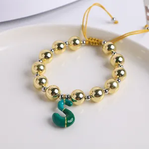 Detalle de cuentas bañadas en oro 18K y dije de letra S en esmalte verde con cordón