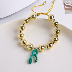Detalle de cuentas bañadas en oro 18K y cordón amarillo con dije de letra A verde