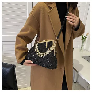 Gros plan sur sac bandoulière à paillettes noires avec chaîne dorée et texture matelassée
