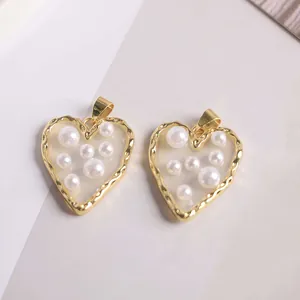Close-up of 18K gold plated heart pendants with textured edges and inlaid pearls