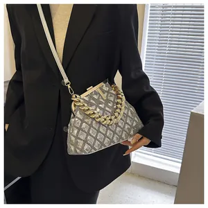 Femme en blazer noir portant un sac à main argenté pailleté avec détails de chaîne dorée