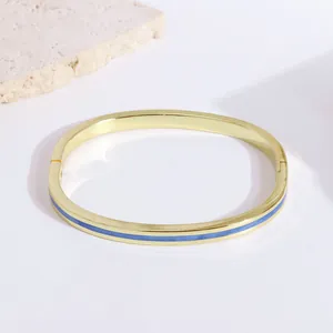 Detail of 18K gold-plated oval bangle featuring blue enamel inlay and a hinge clasp