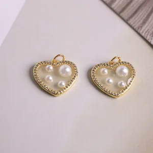 Macro detail of 18K gold plated heart charm with faux pearls and micro-pave crystals