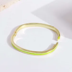 Detail of 18K gold-plated hinged bangle with vibrant neon green enamel stripes