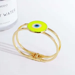 Detail eines 18K vergoldeten Evil Eye Armreifs mit grünem Emaille und Parfümflasche