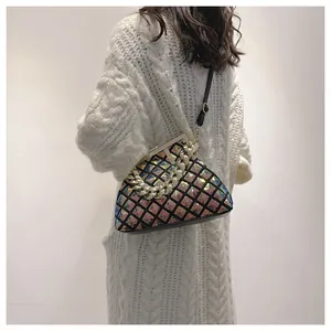 Détail d'un sac bandoulière pailleté arc-en-ciel avec fermoir métallique sur pull blanc