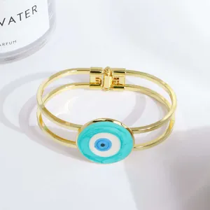 Nahaufnahme des 18K vergoldeten Evil Eye Armbands mit flexiblem Metallschnallen-Detail