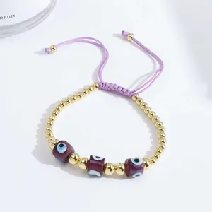 Detail of 18K gold beads and purple evil eye charms on an adjustable braided bracelet