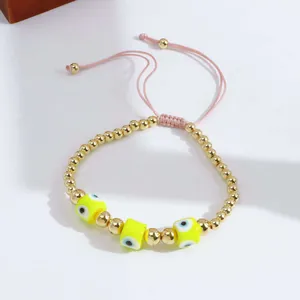Detail of adjustable evil eye bracelet with golden beads and pink braided cord closure