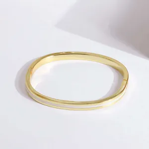 Detail of 18K gold plated bangle with white enamel inlay and secure hinge closure