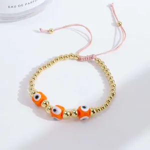 Detailed view of adjustable evil eye bracelet with gold copper beads and orange charms