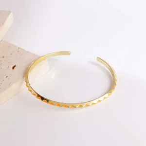 Detail eines 18K vergoldeten Armreifs mit orangefarbenem Emaillemuster auf Stein