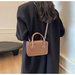 Vista posteriore di una modella con borsa rettangolare marrone in pelle e tracolla