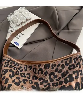 Detailed close-up of leopard print shoulder bag with smooth brown leather strap