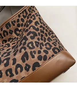 Detail view of leopard print tote bag fabric and brown leather stitching with smooth finish