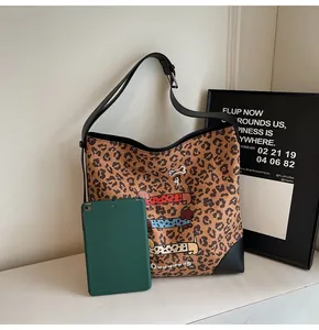 Detail of leopard print tote bag with cartoon dachshunds next to a tablet for size reference