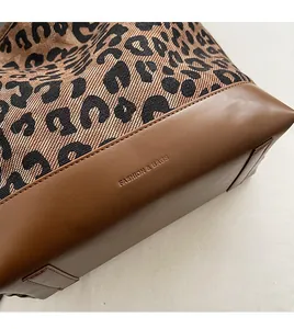 Detailed view of the leopard print canvas tote bag bottom with brown leather and embossing