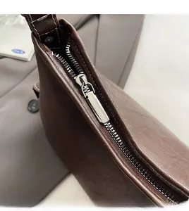 Dettaglio della cerniera in metallo argento e della trama in pelle della borsa marrone