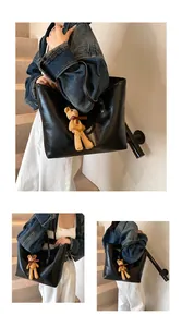 Detail of black quilted tote bag with a cute brown bear charm on the shoulder strap