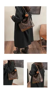 Close-up of leopard print tote bag with faux fur ball charm and silk scarf details