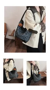 Detail view of leopard print tote bag featuring black leather straps and plush bear charm