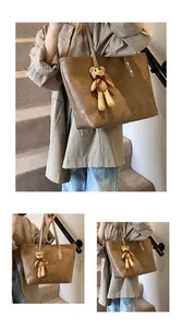Close-up of brown embossed plaid tote bag featuring a cute knitted bear charm accessory