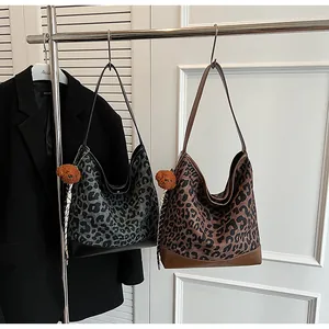 Detail of leopard print hobo bags in grey and brown canvas with plush bear charms